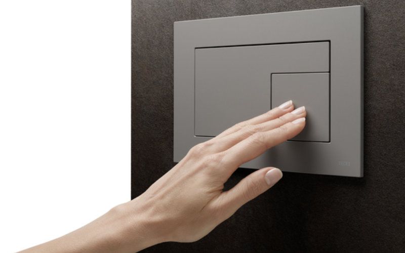 Eine Hand, die eine WC-Betätigungsplatte drückt.
